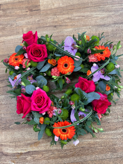 Vibrant Heart Wreath - A colourful open heart tribute filled with bright seasonal blooms, designed to celebrate a vibrant and well-lived life.